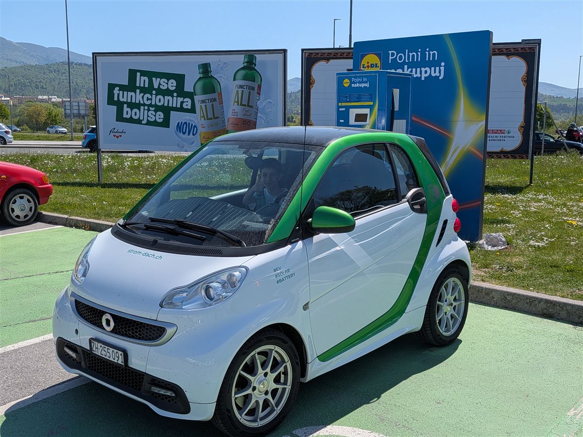 Smart ED at a charge point at a Lidl in Slovenia, mountains behind
